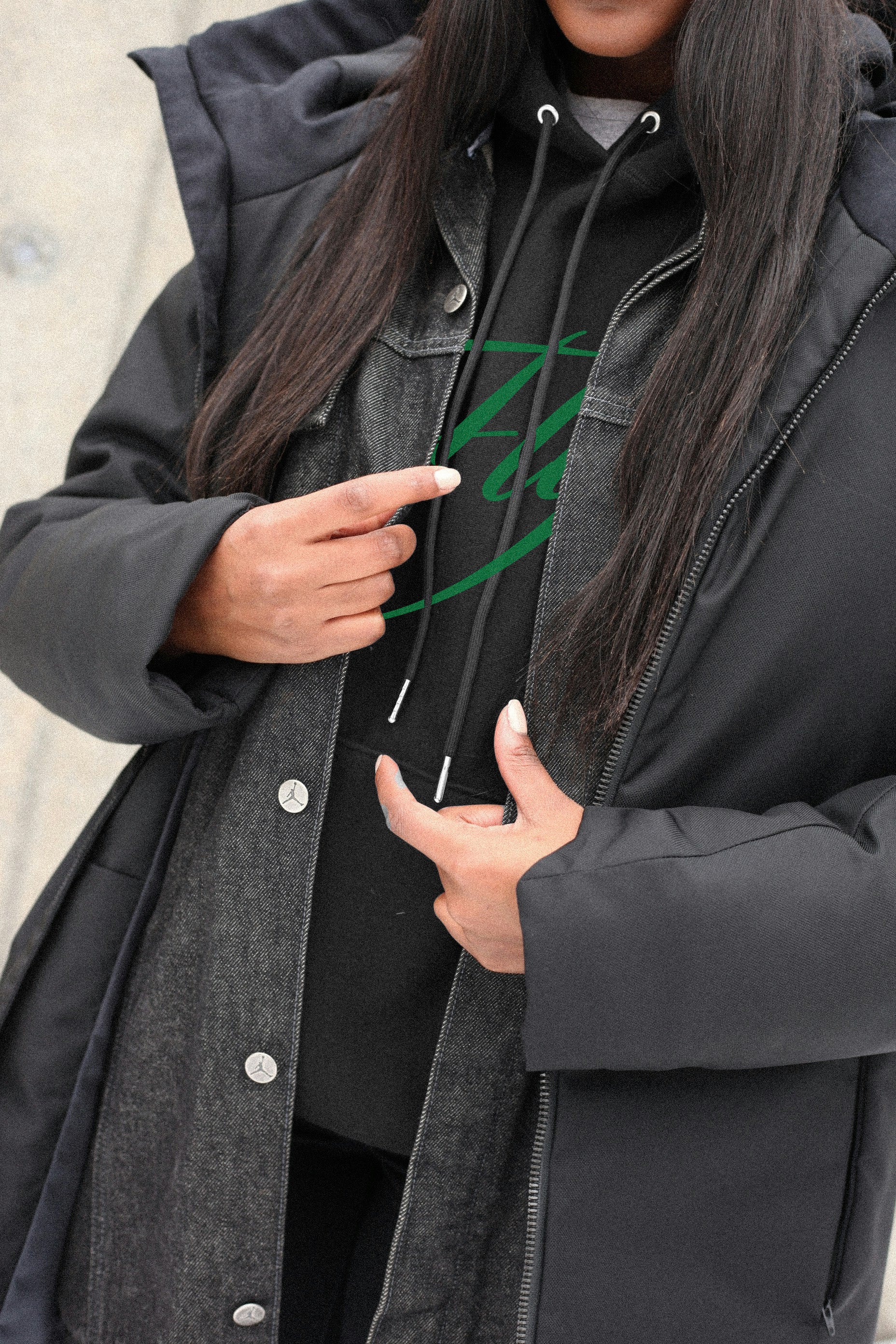 Person wearing a black coat with a brand logo on the chest.