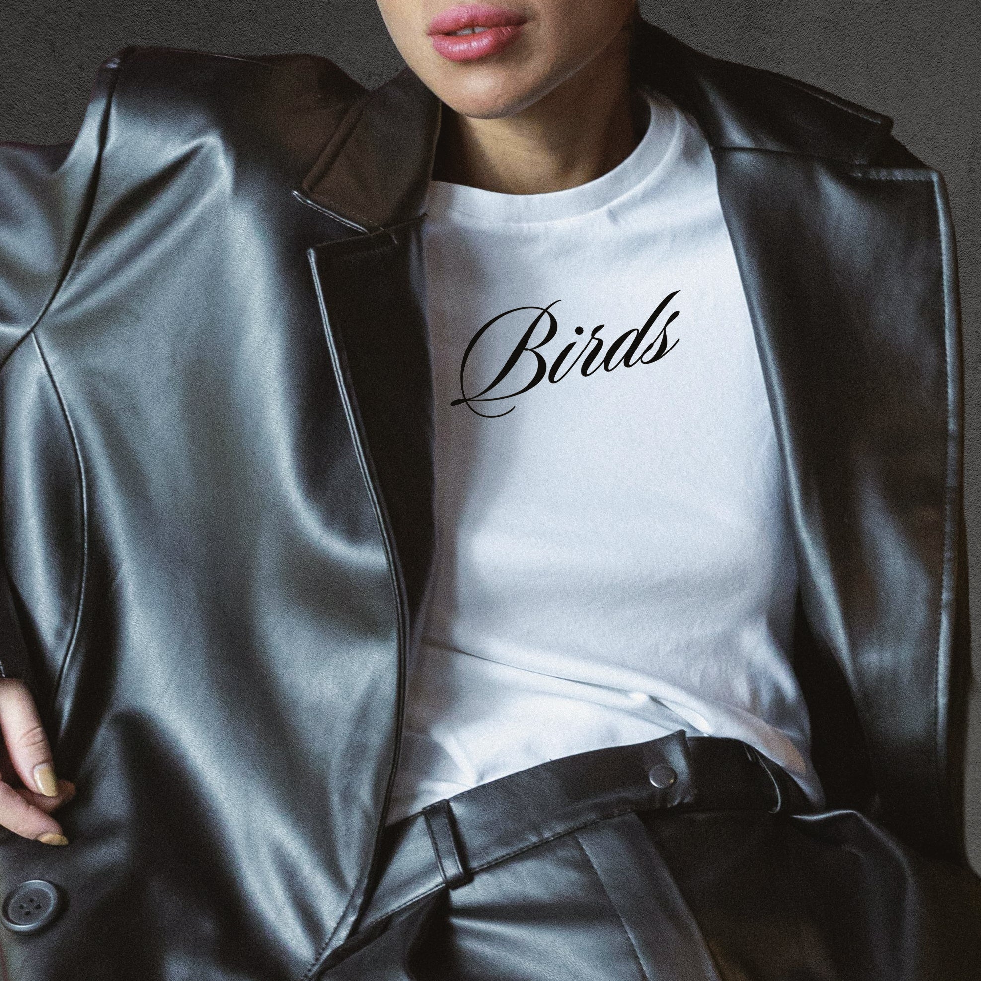 Person wearing a black leather jacket over a white shirt with 'Birds' text on a dark background