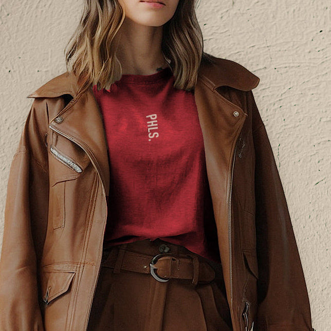 Woman wearing a brown jacket and pants with a red shirt against a beige wall