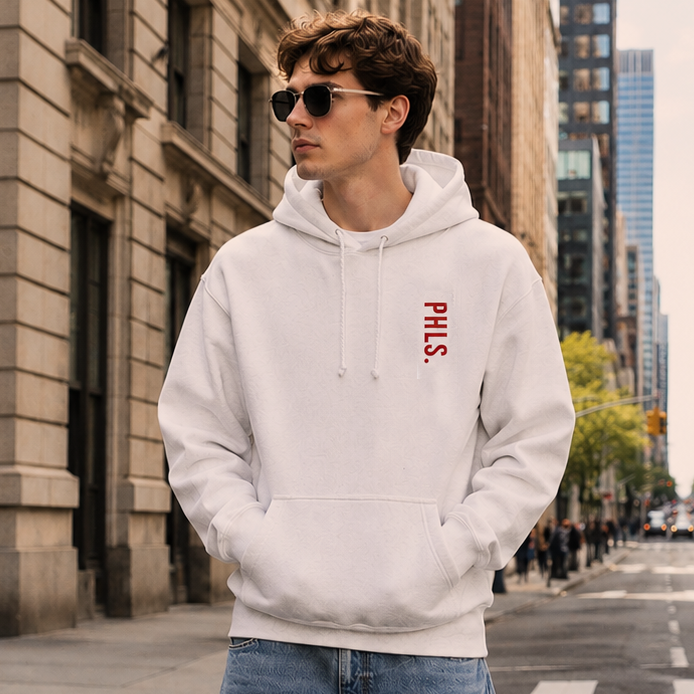 Person wearing a white hoodie with red text and blue shorts standing on a city street.