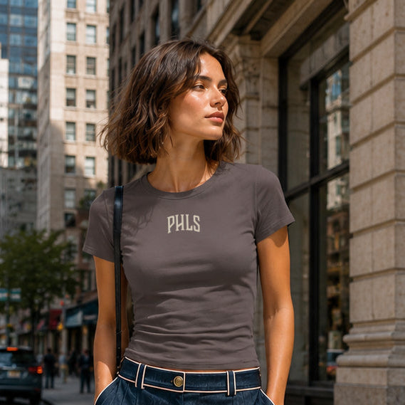 Woman standing on a city street wearing a gray t-shirt and dark blue skirt.
