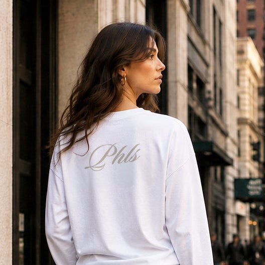 Woman in a white sweatshirt and black skirt standing on a city street.