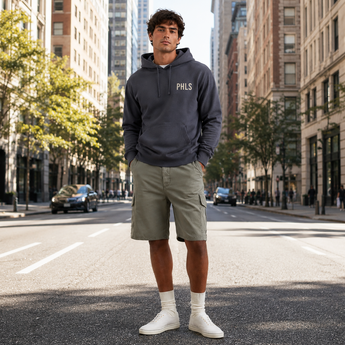 Man wearing a hoodie with 'PHILS' on it standing on a city street.
