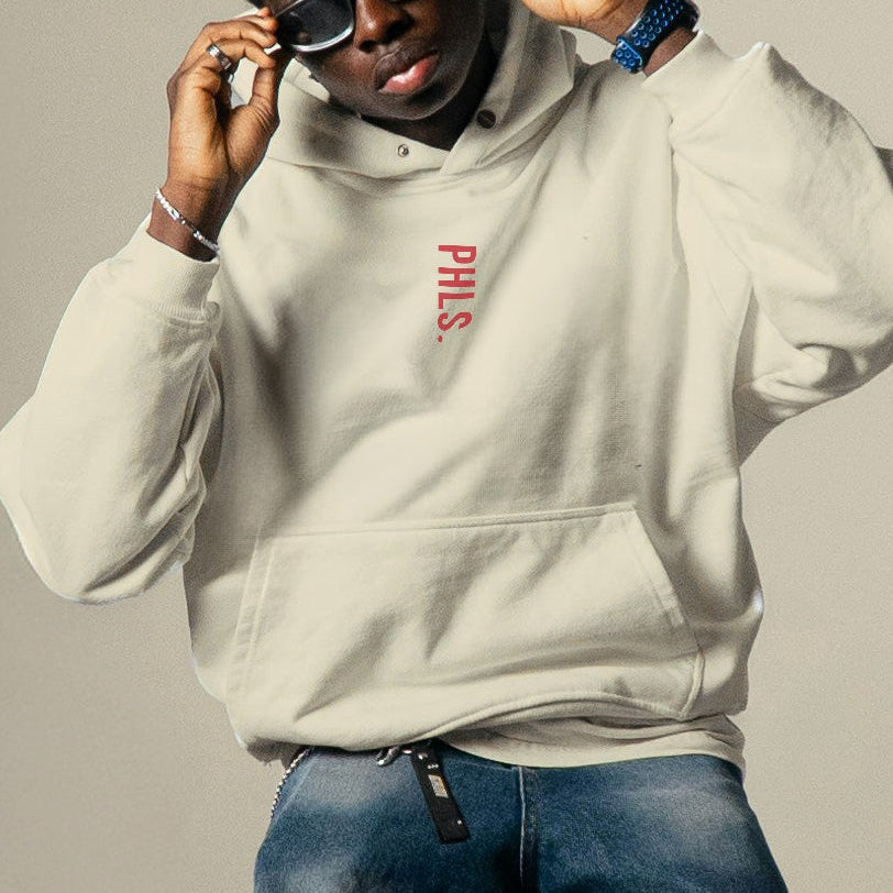 Person wearing a white sweatshirt and blue jeans sitting on a stool against a plain background