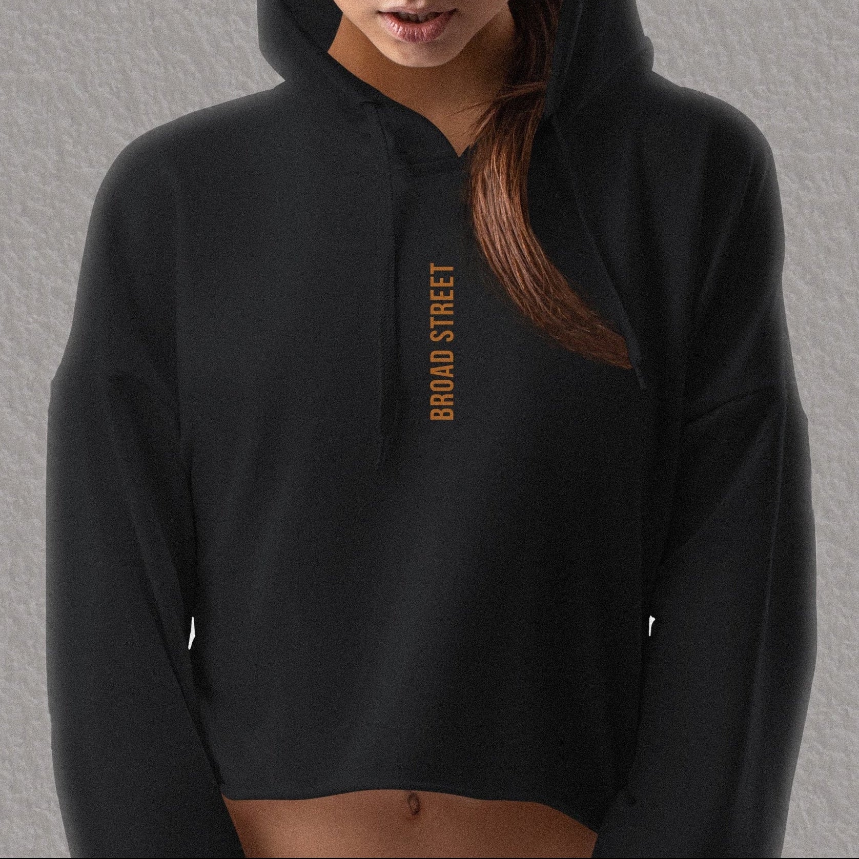 Woman wearing a black hoodie with 'BROAD STREET' text on a gray background