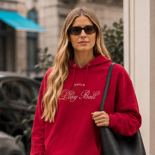 Woman wearing a red hoodie and black shorts on a city street.