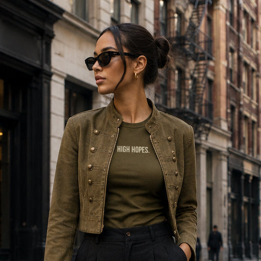 Woman in urban setting wearing a green jacket and black pants.
