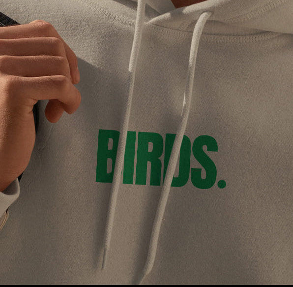 Person wearing a gray hoodie with 'BIRDS.' printed in green.