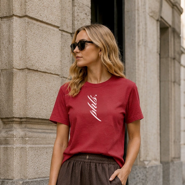 Woman in a red t-shirt and brown wide-leg pants standing on a city street.
