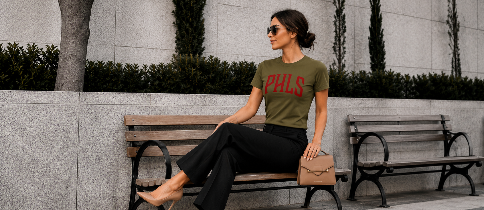 Woman sitting on a bench wearing a green t-shirt with 'PHL' printed on it.