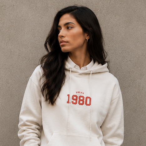 Woman wearing a white hoodie with red text, white shirt, navy skirt, and white shoes against a gray background.