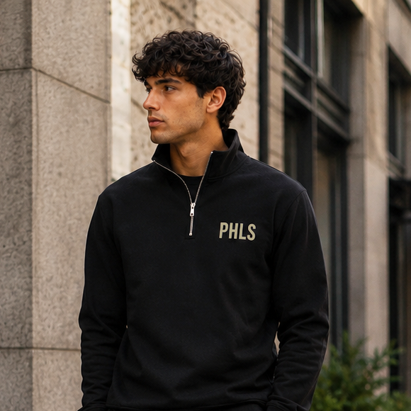Man wearing a black sweatshirt with 'PHLS' logo on a city street.