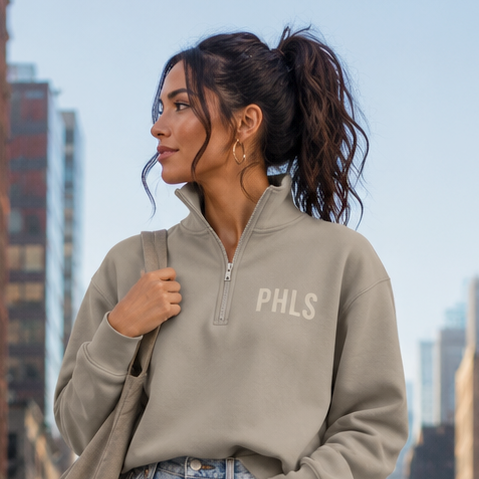 Woman in a gray sweatshirt and denim shorts standing on a city street.