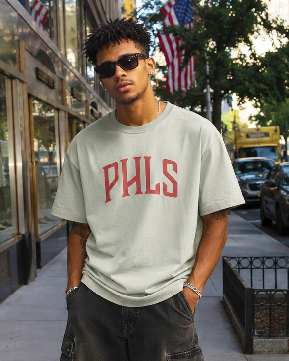 Man wearing a gray 'PHLS' t-shirt on a city street