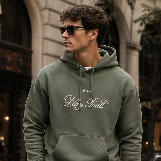 Man in green hoodie and shorts holding a briefcase on a city street