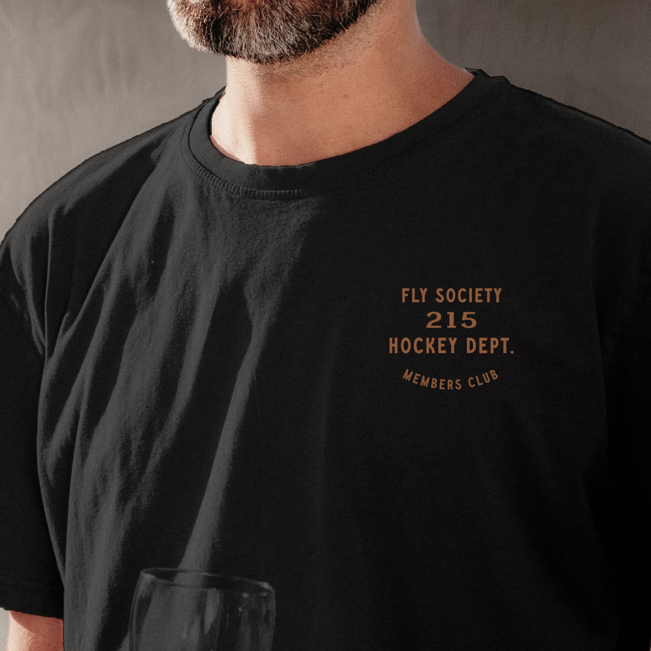 Man wearing a black t-shirt with text on a neutral background