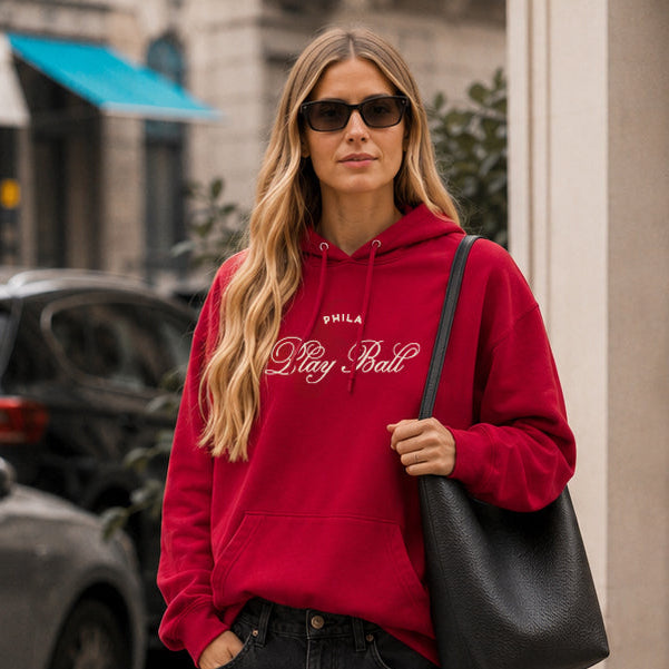 Woman wearing a red hoodie and black shorts on a city street.